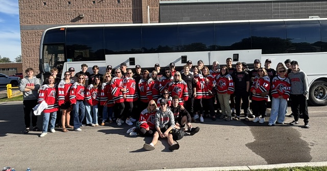 Riverhawks players, families and staff in front of the team bus